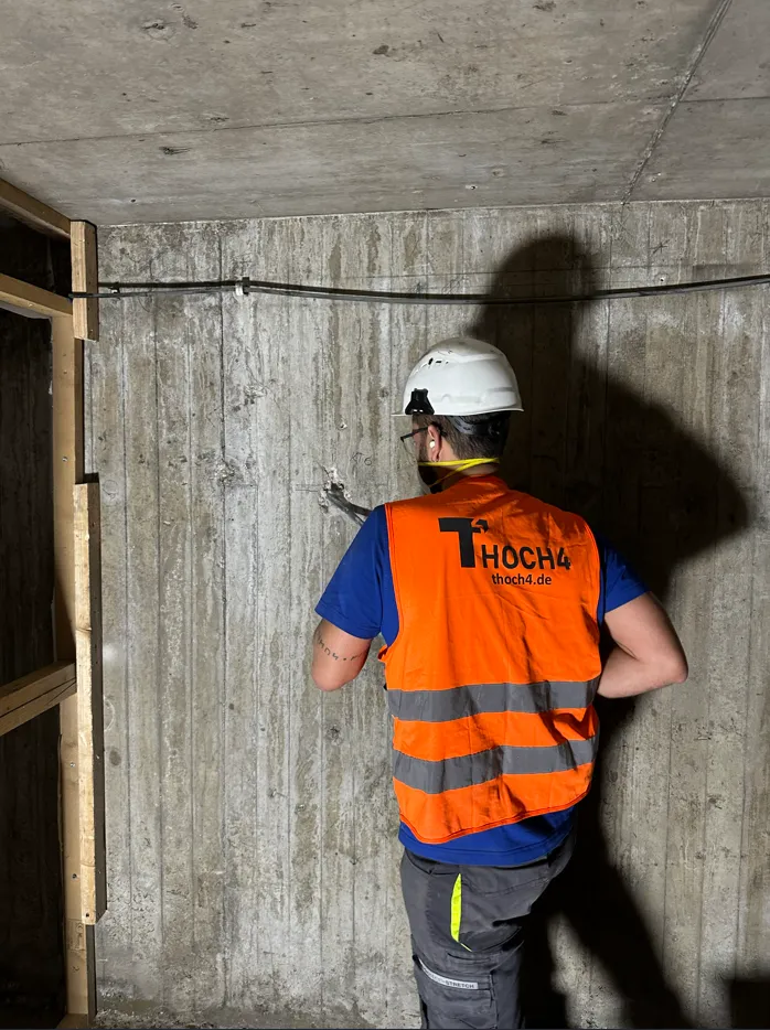 thoch4 Ingenieur bei der Bauwerksuntersuchung an einer Betonwand